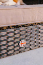 Raised pet bed cushion edge on dark rattan weave side with gold trim