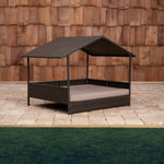 Outdoor raised pet bed with dark brown woven wicker frame and beige cushion