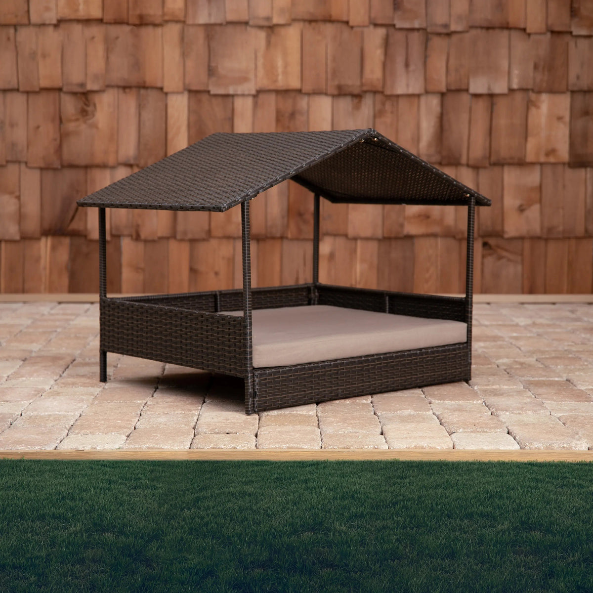 Outdoor raised pet bed with dark brown woven wicker frame and beige cushion