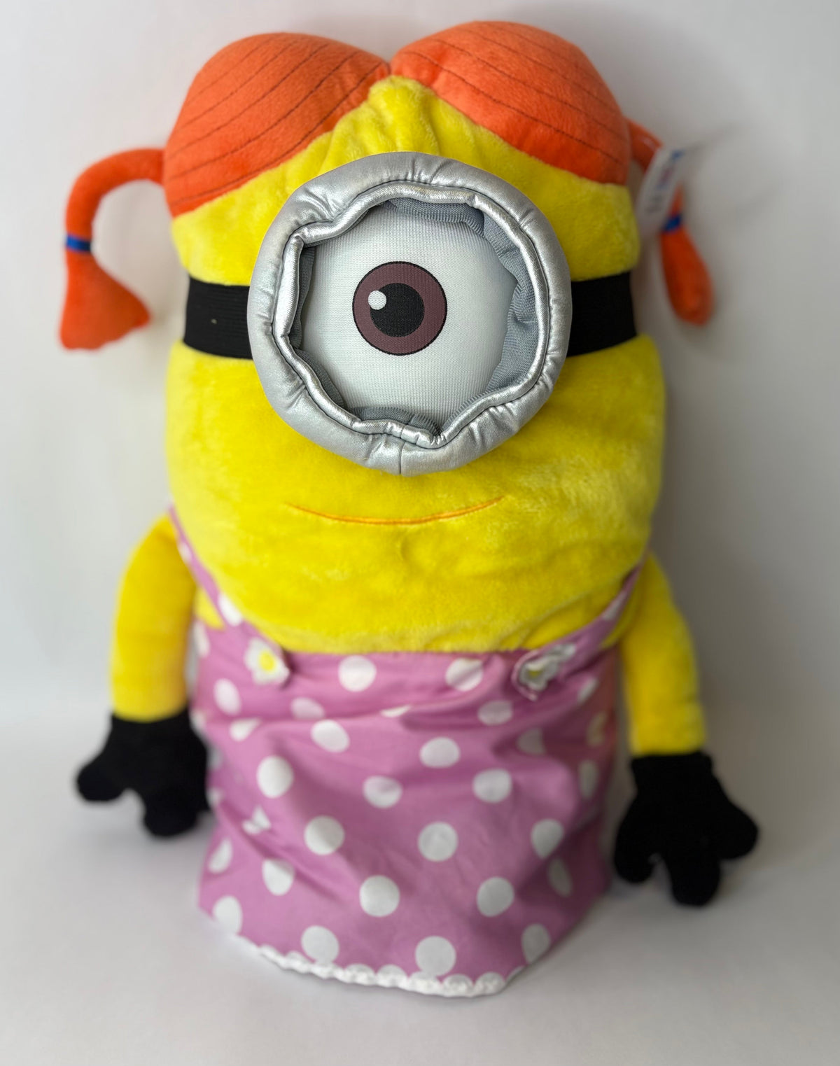 Yellow Minion plush wearing an orange hood and pink polka-dot dress