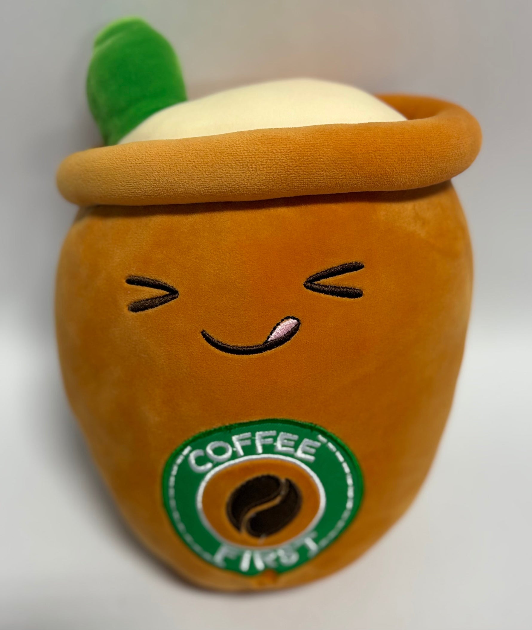 Large orange plush drink character with smile face and green “Coffee” badge