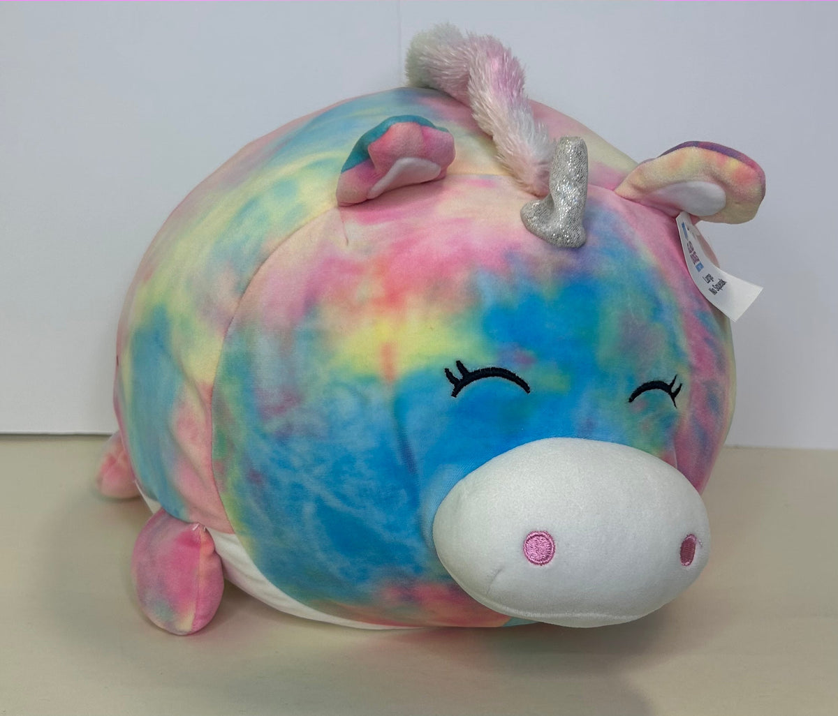 Large pastel rainbow squishy unicorn plush with silver horn and closed eyes