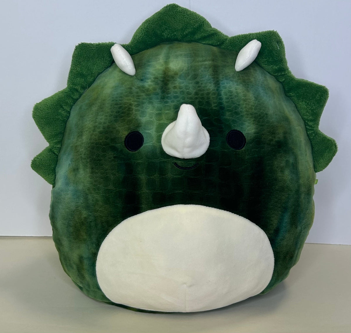 Large green dinosaur squishy plush with white snout and rounded horn details