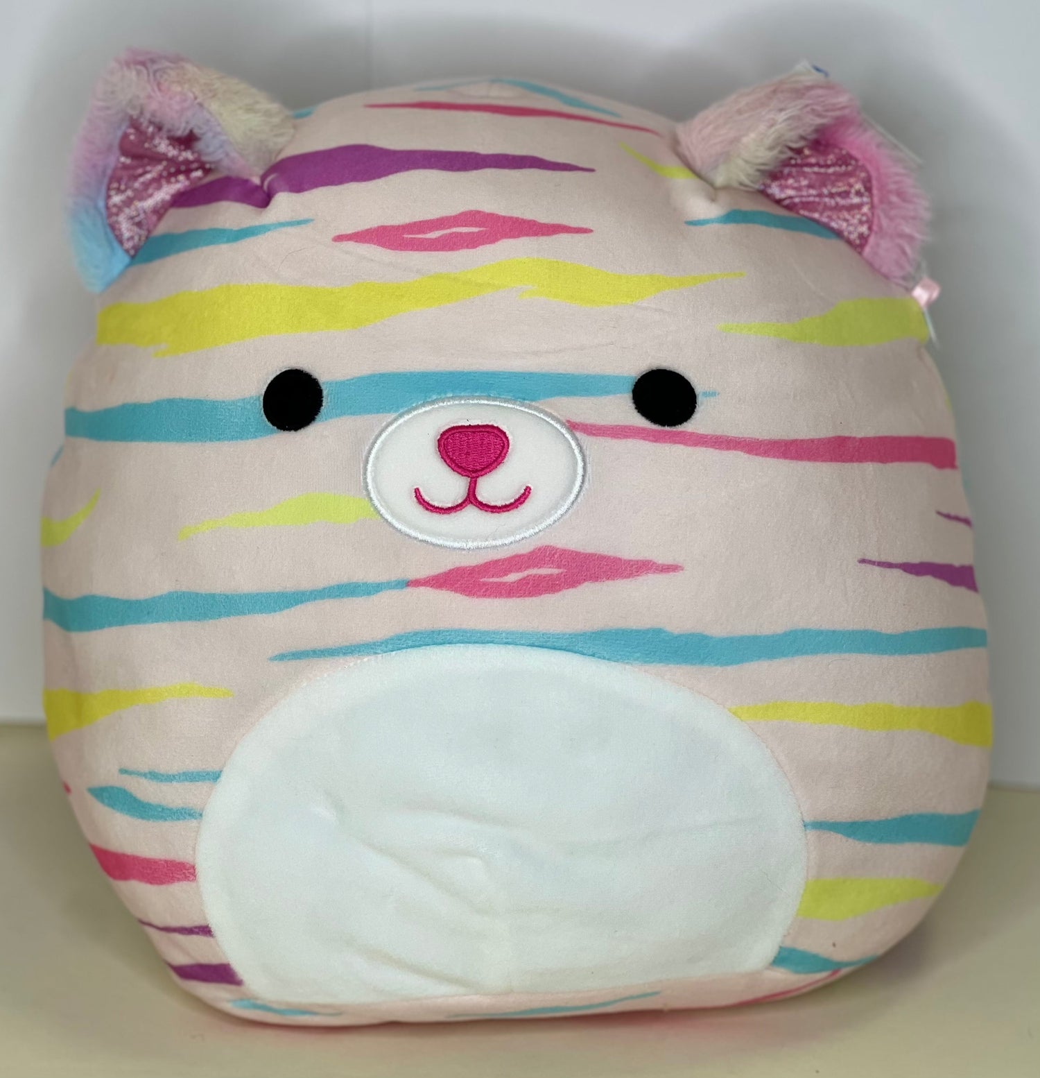 Striped pastel plush squishy pet toy with embroidered smile and heart-like nose badge