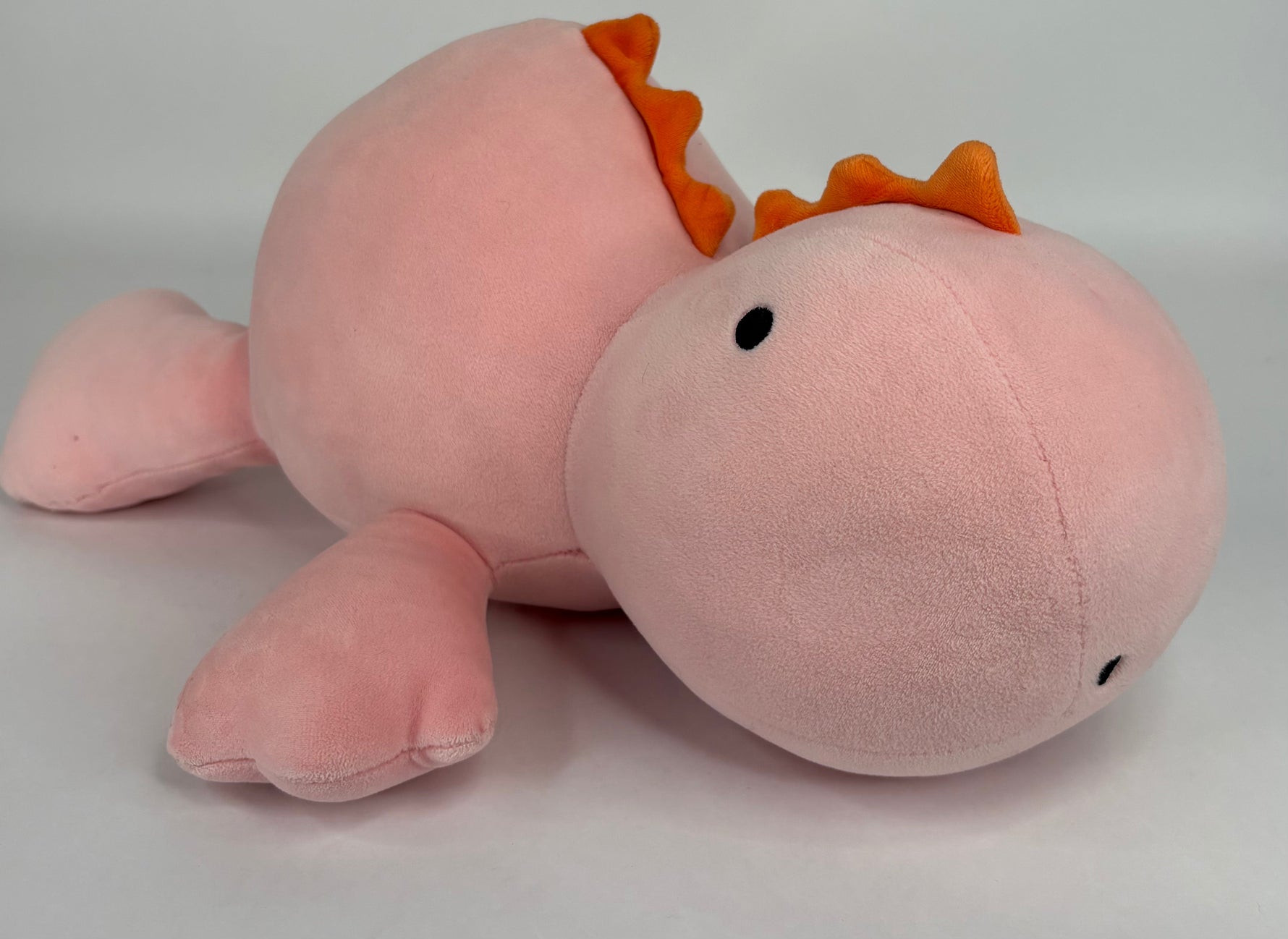 Large pink plush narwhal-like character with orange fins and small black eye