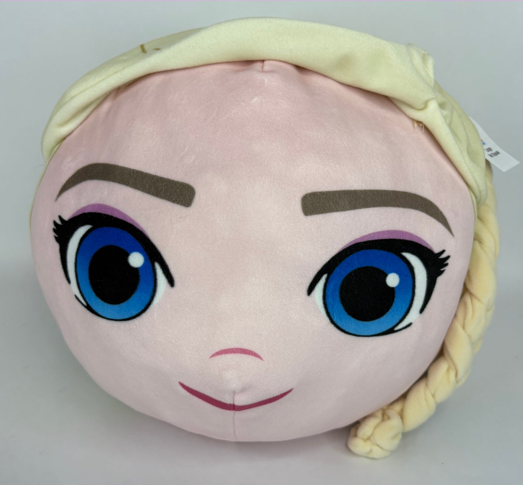 Large light pink plush character head with blue eyes, purple brows, and blonde hat