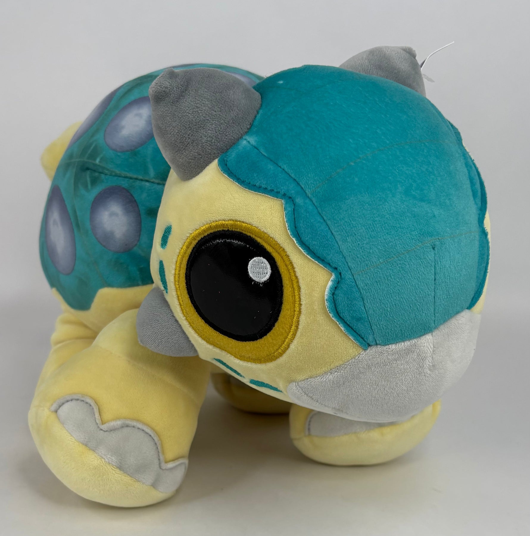 Large teal and gray plush creature with big eye and long floppy body