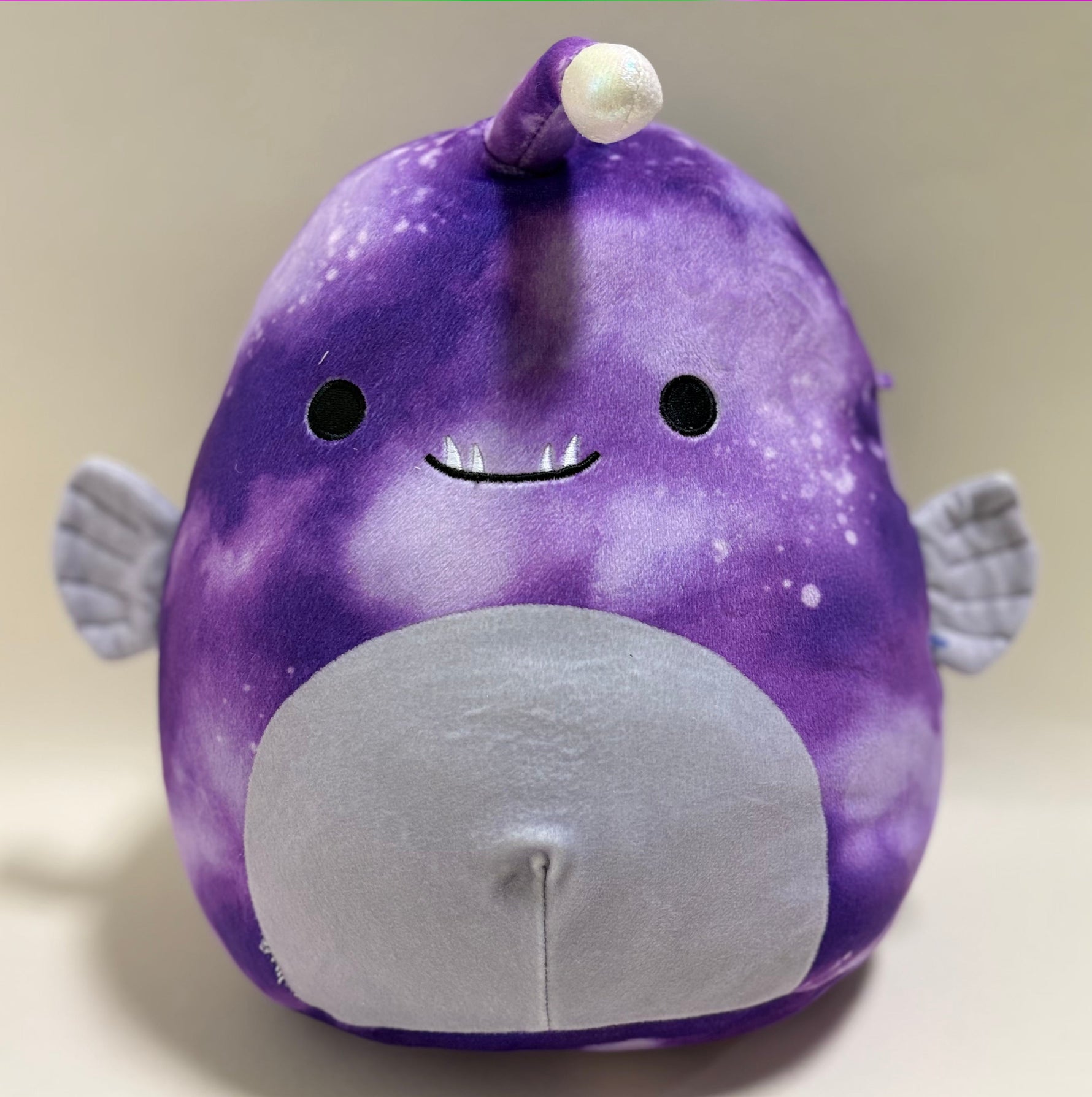 Purple whale plush with smiling face and large gray belly patch