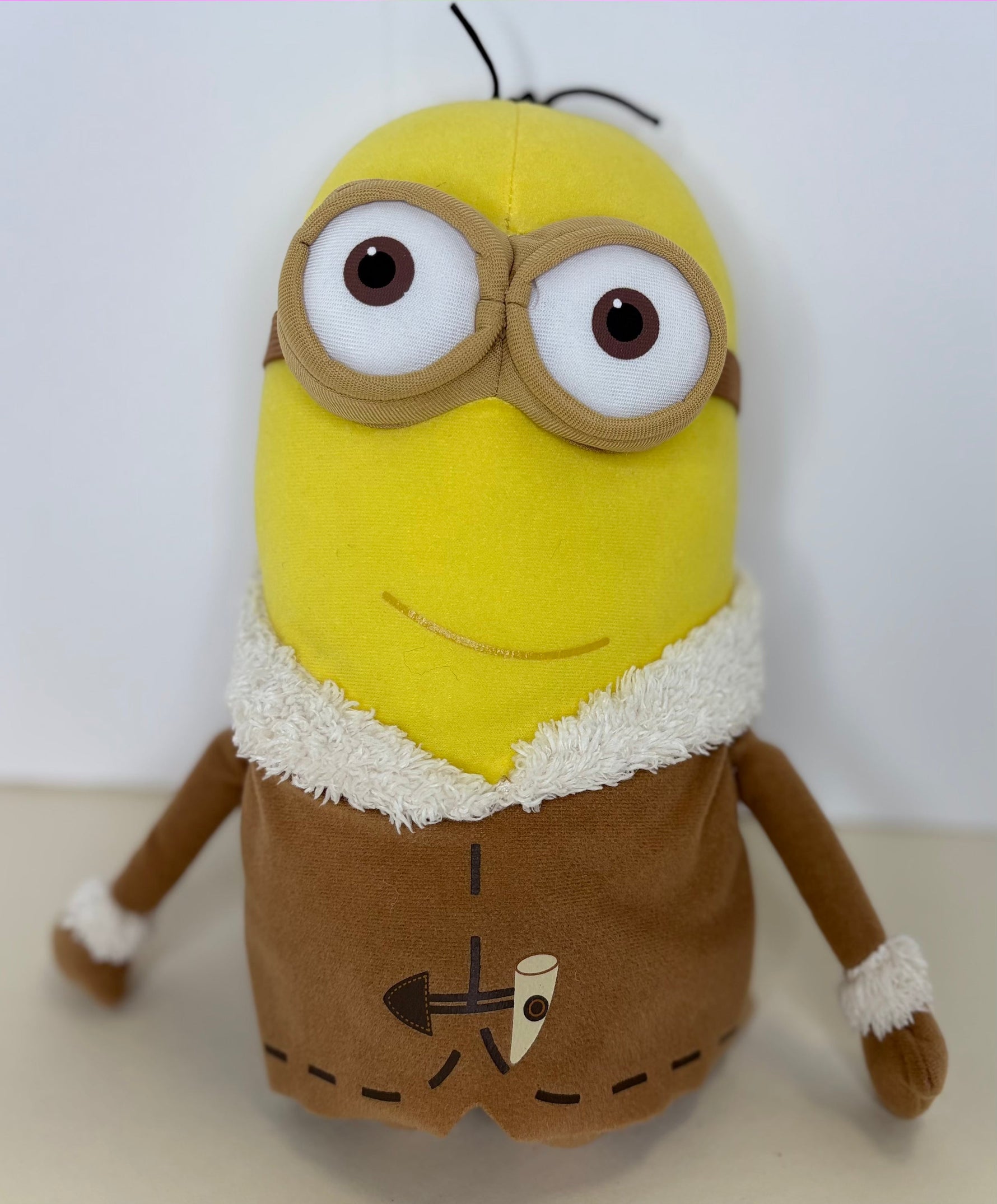 Yellow minion plush in brown outfit with tan face, large goggles, and fuzzy trim