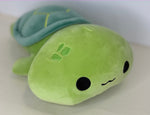 Green plush cuddler with small fin, black eye, and gentle smile on rounded body