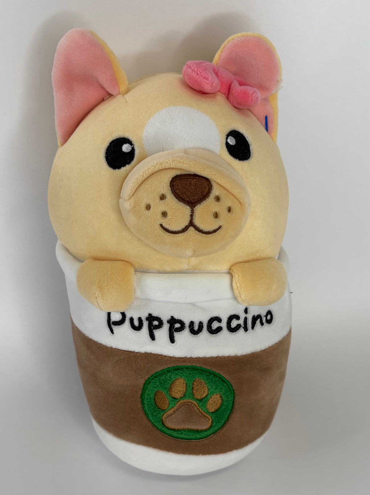 Beige dog plush cuddler with pink bow and 'Puppuccino' front patch with paw logo