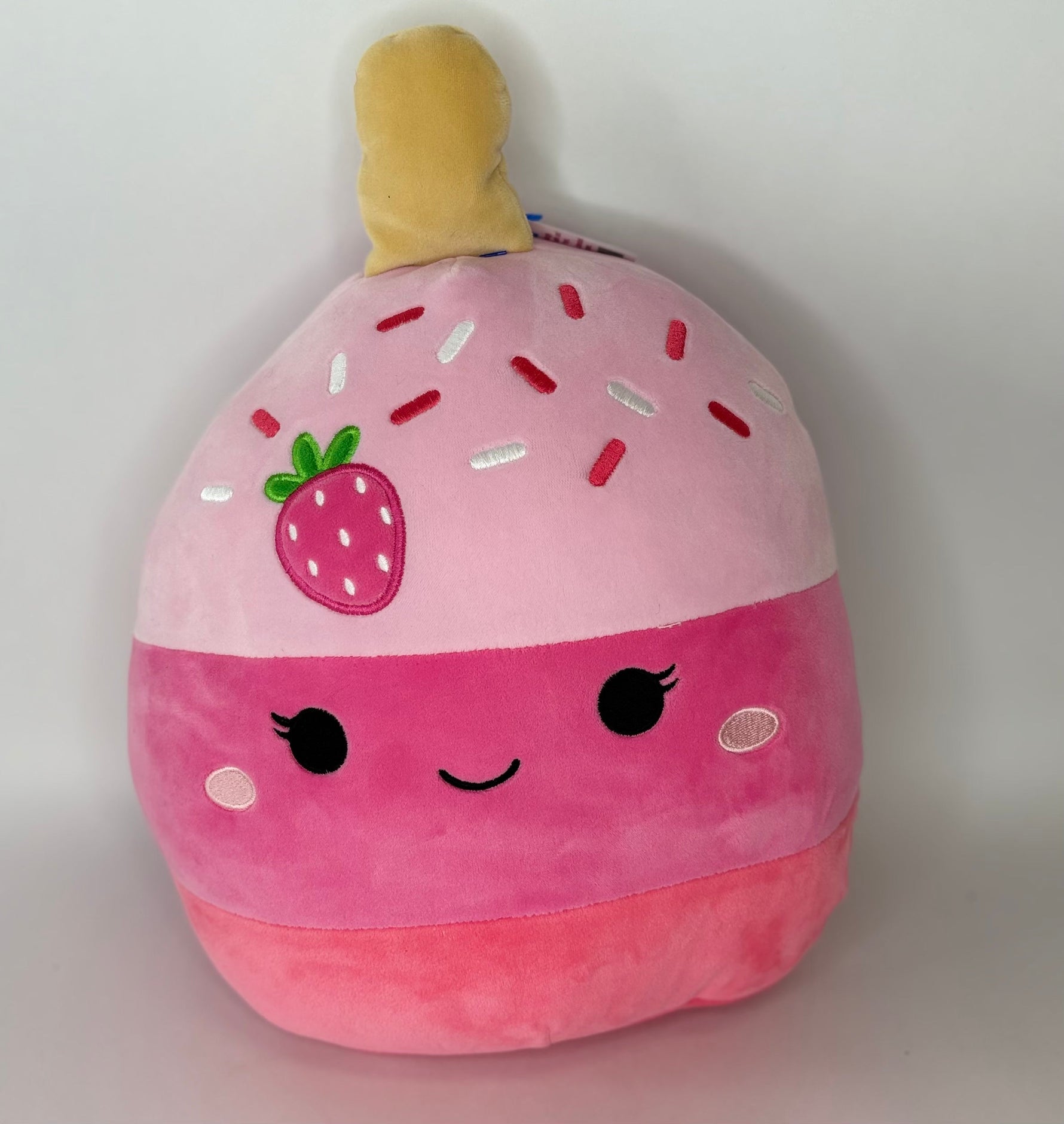 Large pink strawberry plush pet toy with smiling face and squishy body