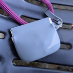 Gray silicone treat pouch close-up with purple strap and embossed brand mark.