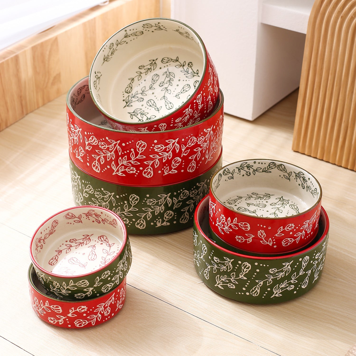 Stacked ceramic pet bowls with wooden stands, red and green garden-pattern bowls