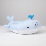 Plush whale-shaped pet bed in light blue with striped base, snout fins, and raised tail