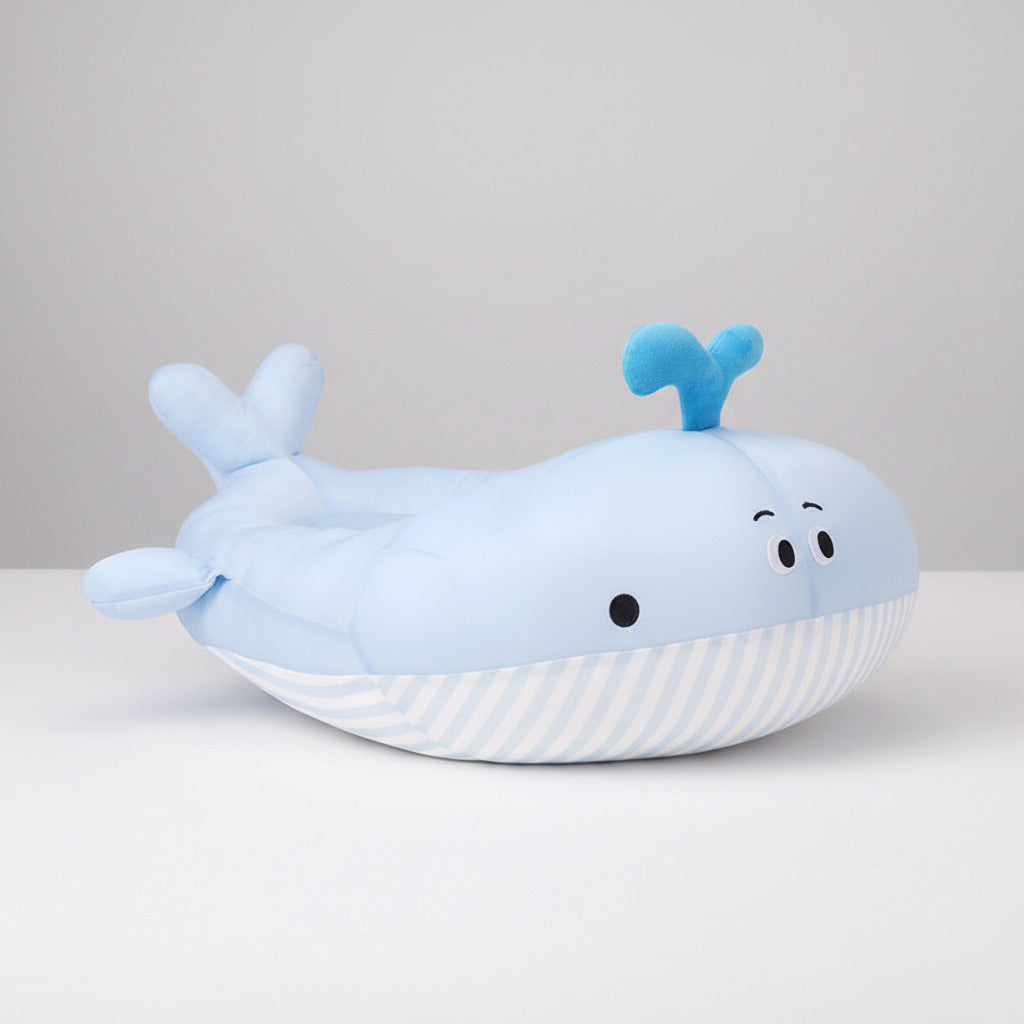 Plush whale-shaped pet bed in light blue with striped base, snout fins, and raised tail