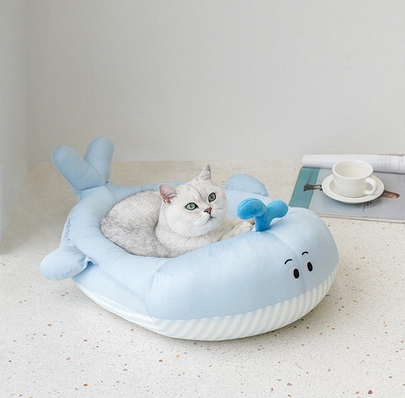 Plush whale-shaped pet bed with light blue top, striped base, fin and tail; cat inside