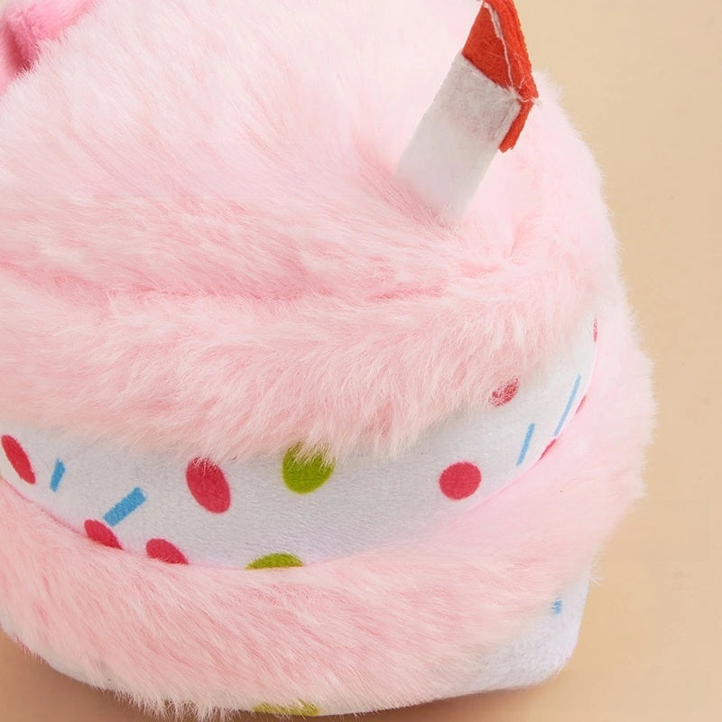 Pink plush birthday-cake dog toy with candle and sprinkle band