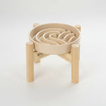 Beige wave slow feeder dog bowl on a wood stand with raised channels