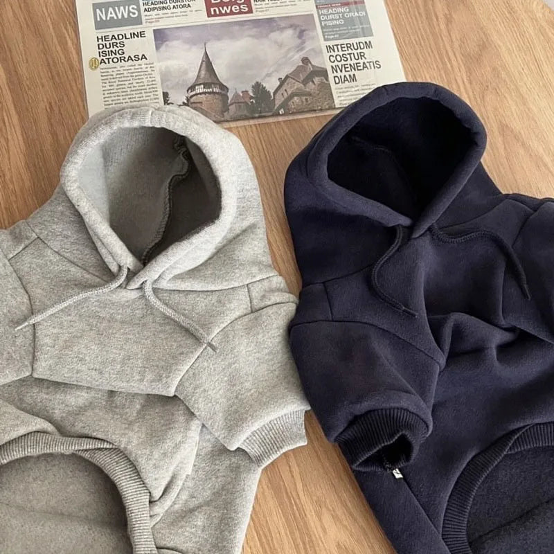 Close-up of light grey and navy dog hoodies with drawstrings and front pockets