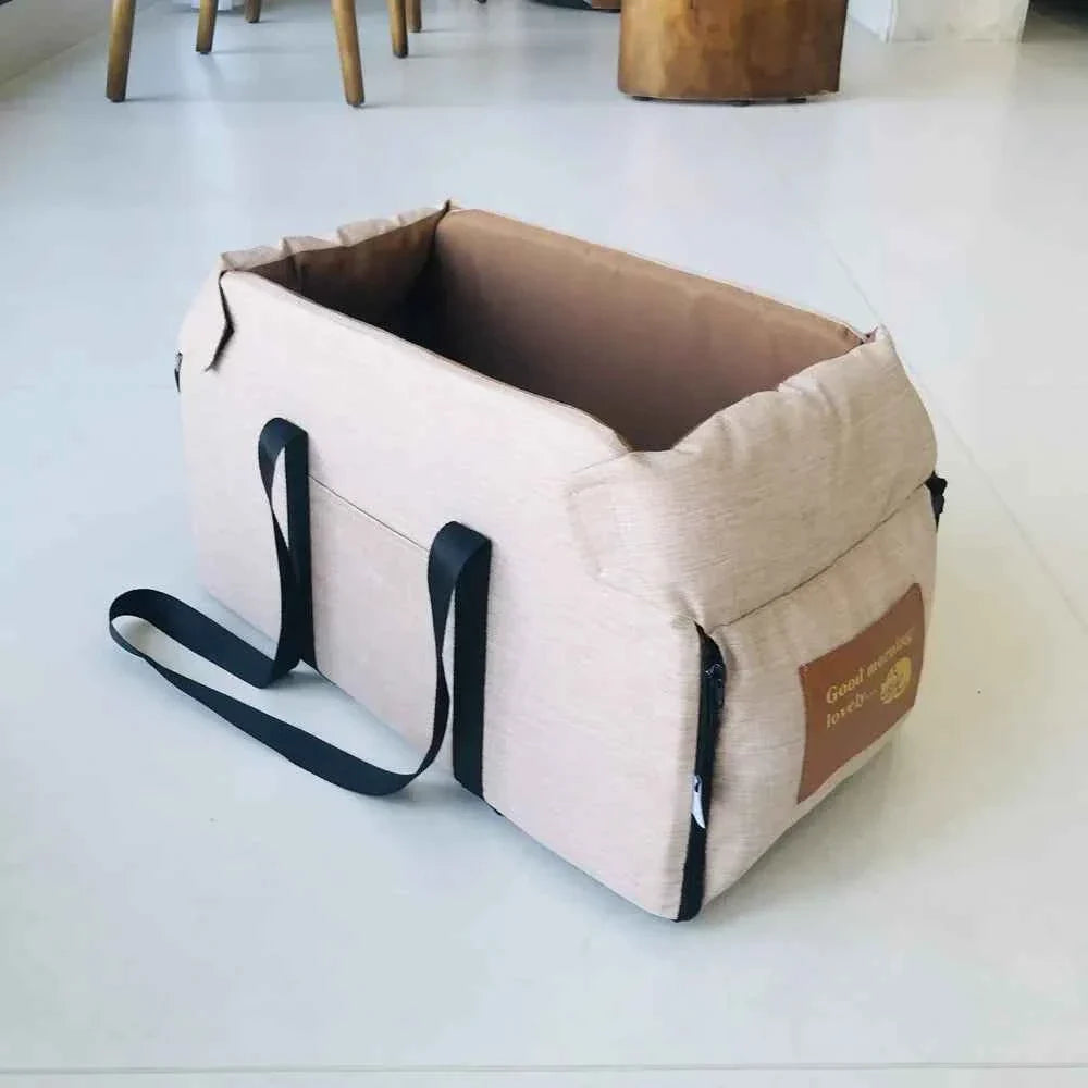 Khaki pet car seat bed with black handles, zippered front panel, and padded interior