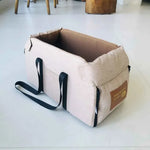 Khaki pet car seat bed with black handles, zippered front panel, and padded interior