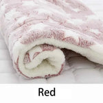Red flannel pet sleeping mat with paw-print swirl pattern and soft cream inner lining
