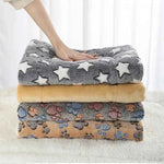 Flannel pet sleeping mat stack, grey star top with beige paw-pattern layer underneath