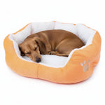 Orange round pet bed with white plush liner and paw emblem, brown dog sleeping inside