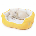 Yellow round pet bed with white plush liner and paw emblem, cat sleeping inside