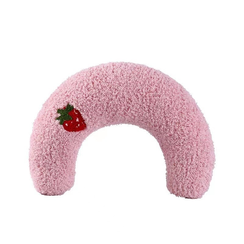Pink plush U-shaped cat pillow toy with a red fruit patch