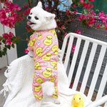 White dog wearing pink duck-pattern four-legged pet outfit with long sleeves