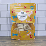 Freeze-dried banana dog treats pouch, yellow with paw/bone print; open view treats
