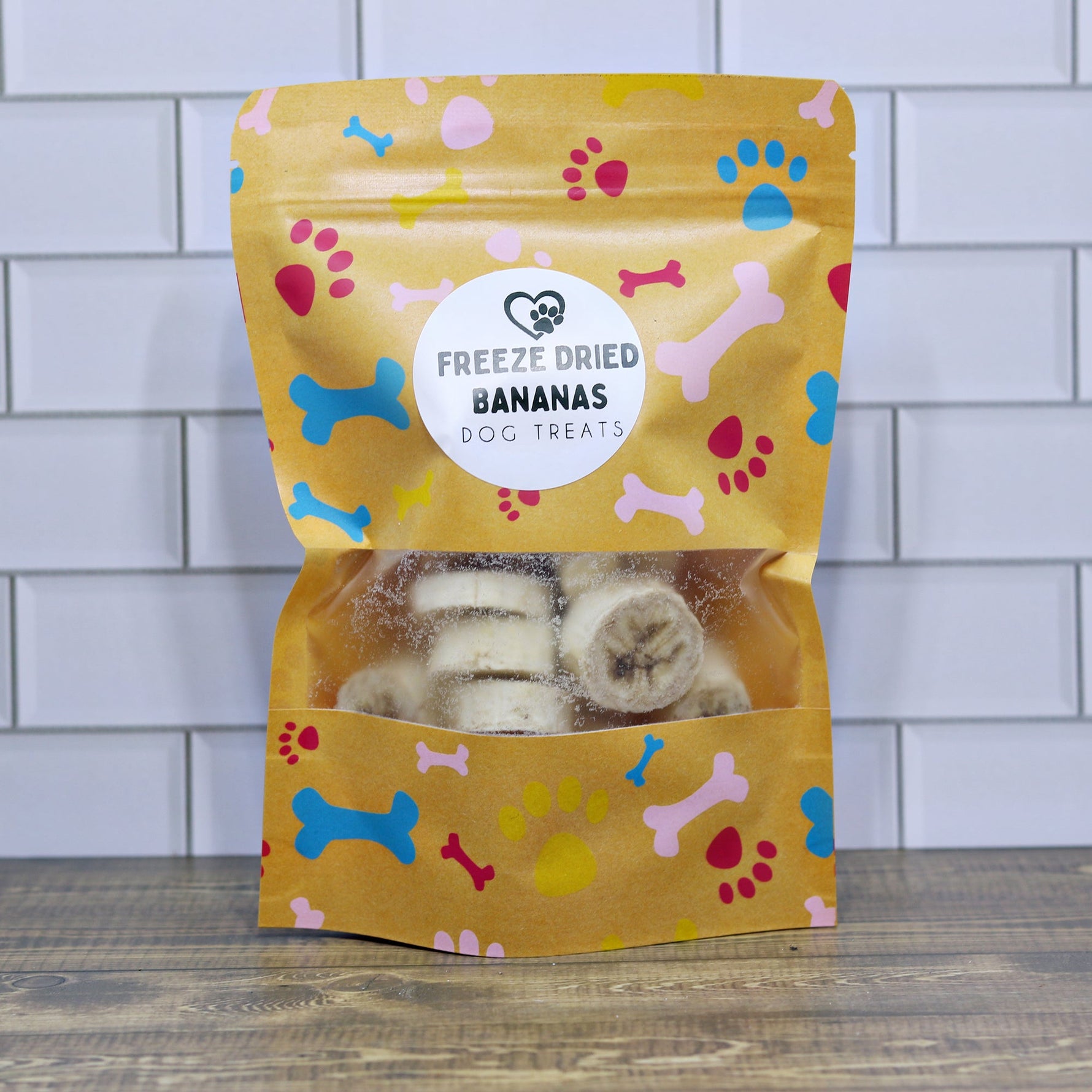 Freeze-dried banana dog treats pouch, yellow with paw/bone print; open view treats