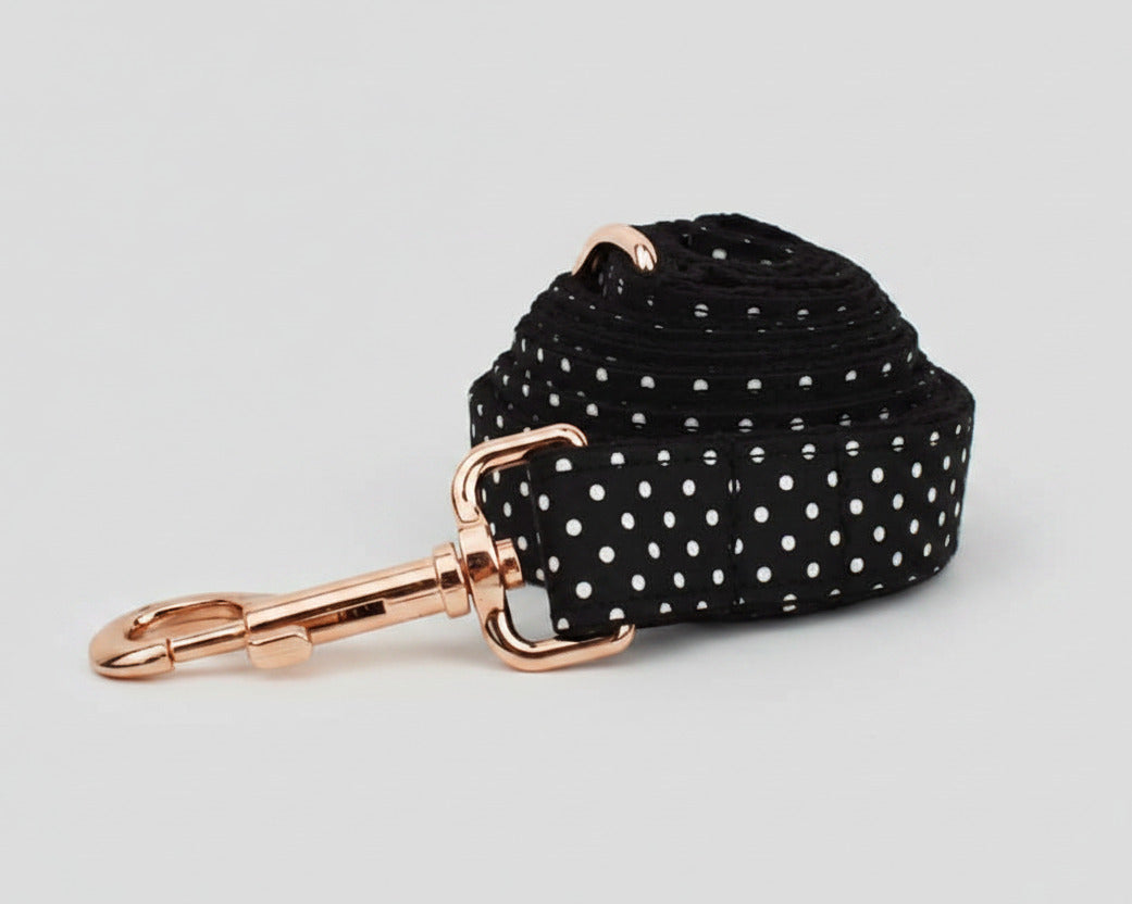 Black polka-dot leash strap with rose-gold clip and swivel; coiled for display