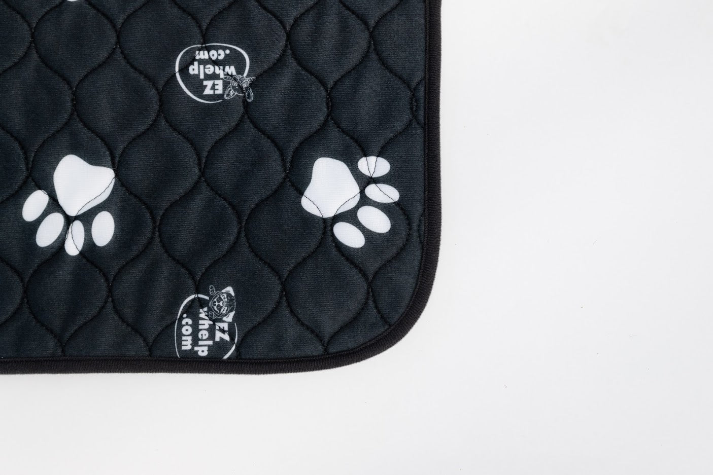 Black pet mat corner with white paw prints and stitched edge