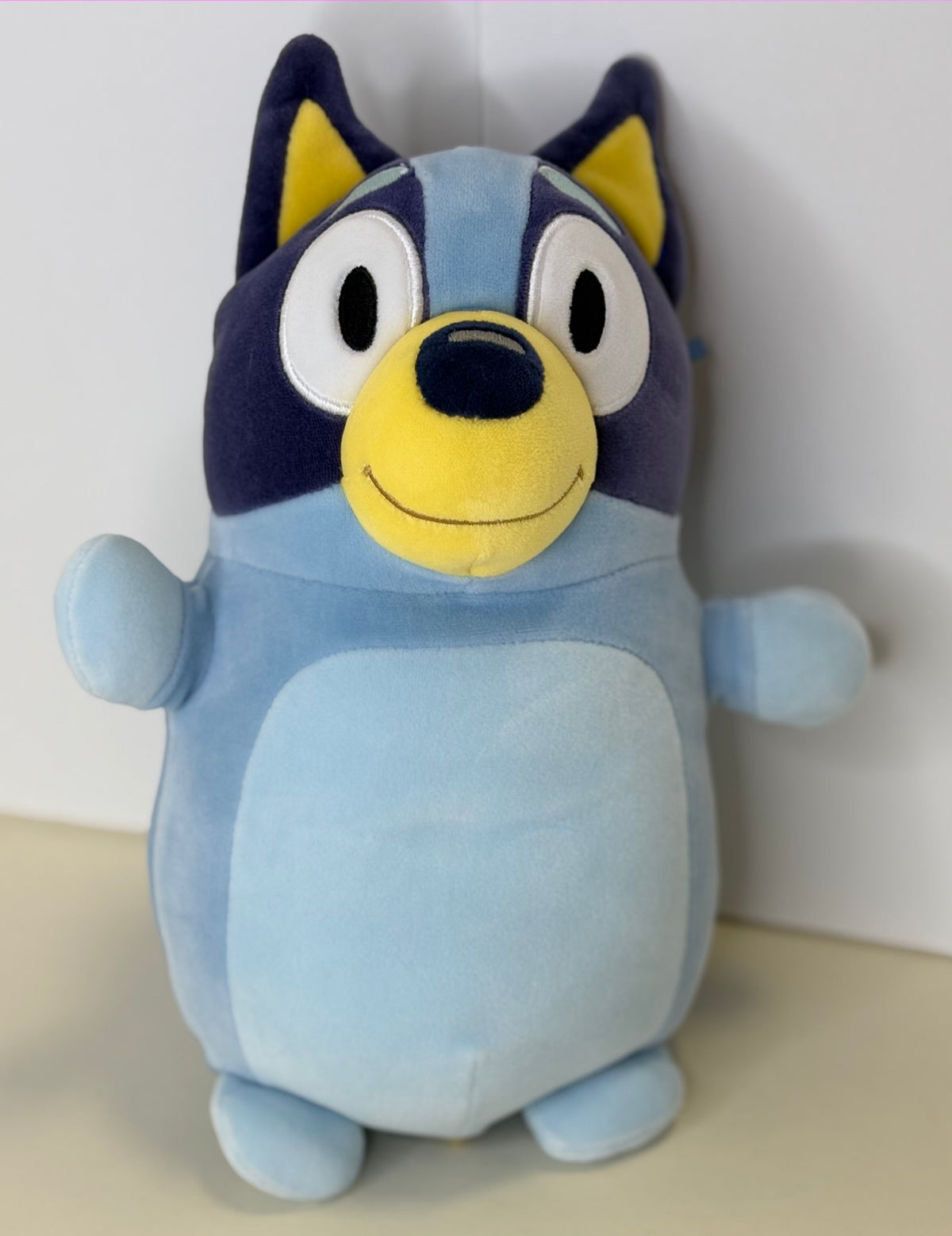 Light blue plush cuddler with yellow muzzle, big ears, and embroidered smiling face
