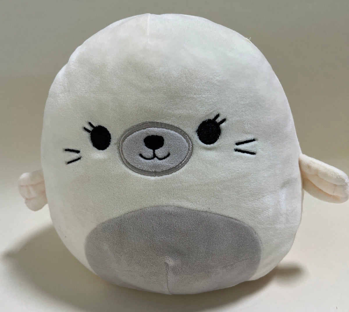 Large squishy plush pet toy, white seal with gray snout and stitched smile.