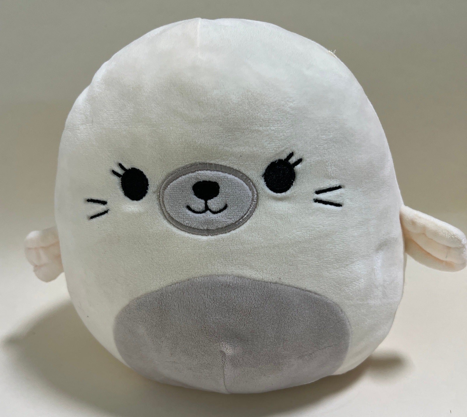 Large squishy plush pet toy, white seal with gray snout and stitched smile.