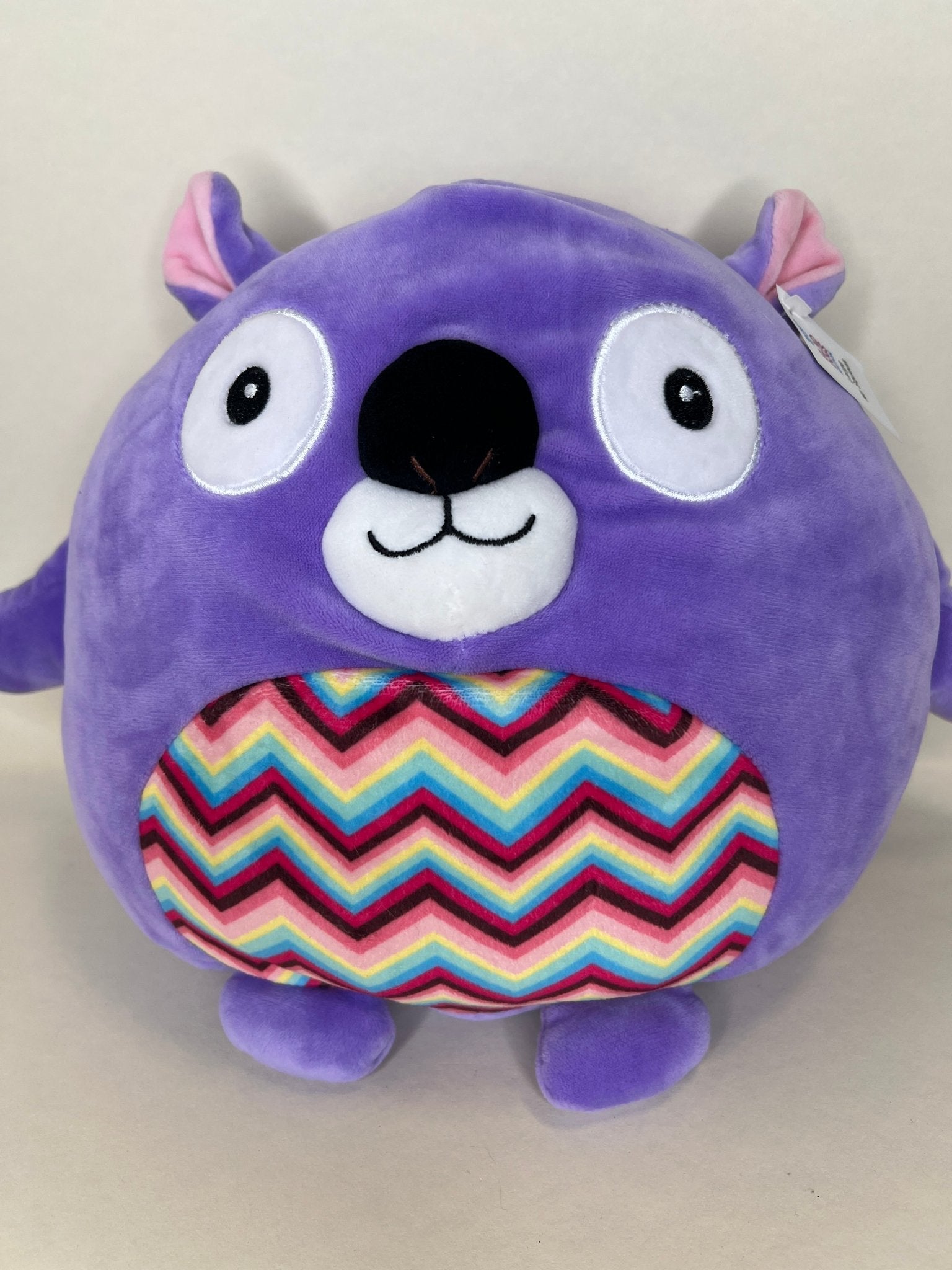 Large purple plush cuddler with big eyes and rainbow belly panel, squishy design