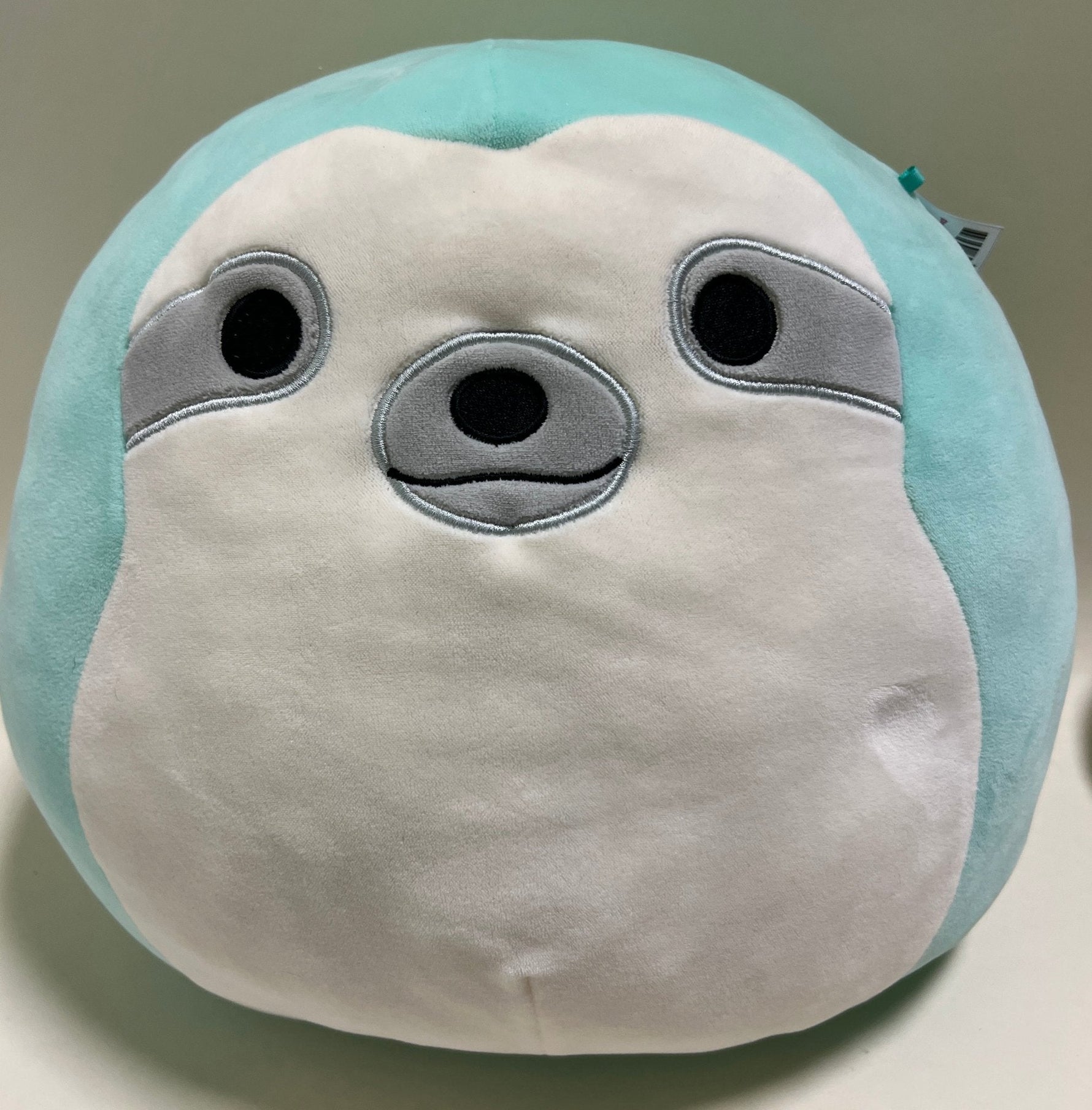 Turquoise-and-white plush seal with round black eyes and gray snout