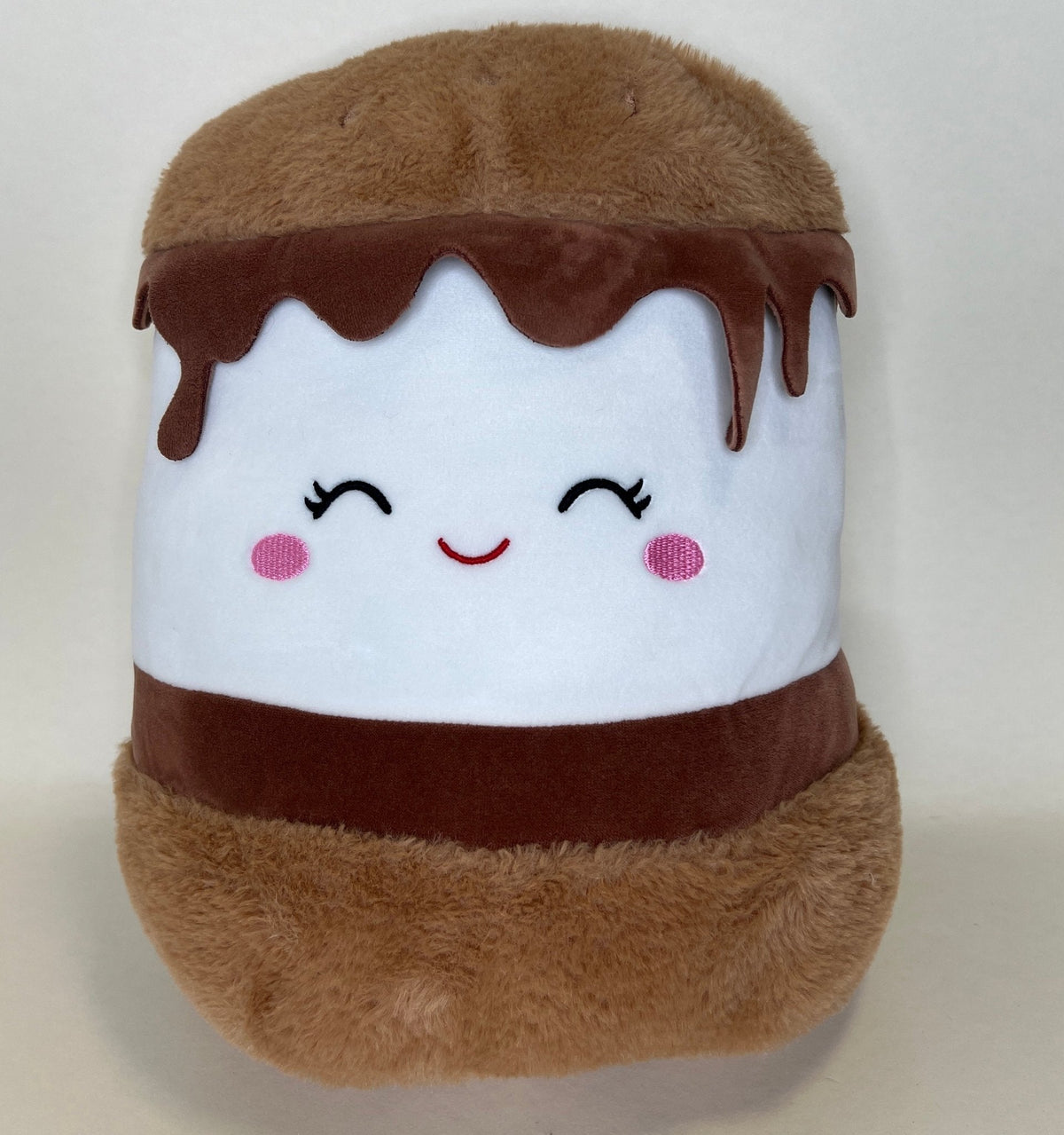 Brown and white plush dessert with closed eyes, rosy cheeks, and drippy top