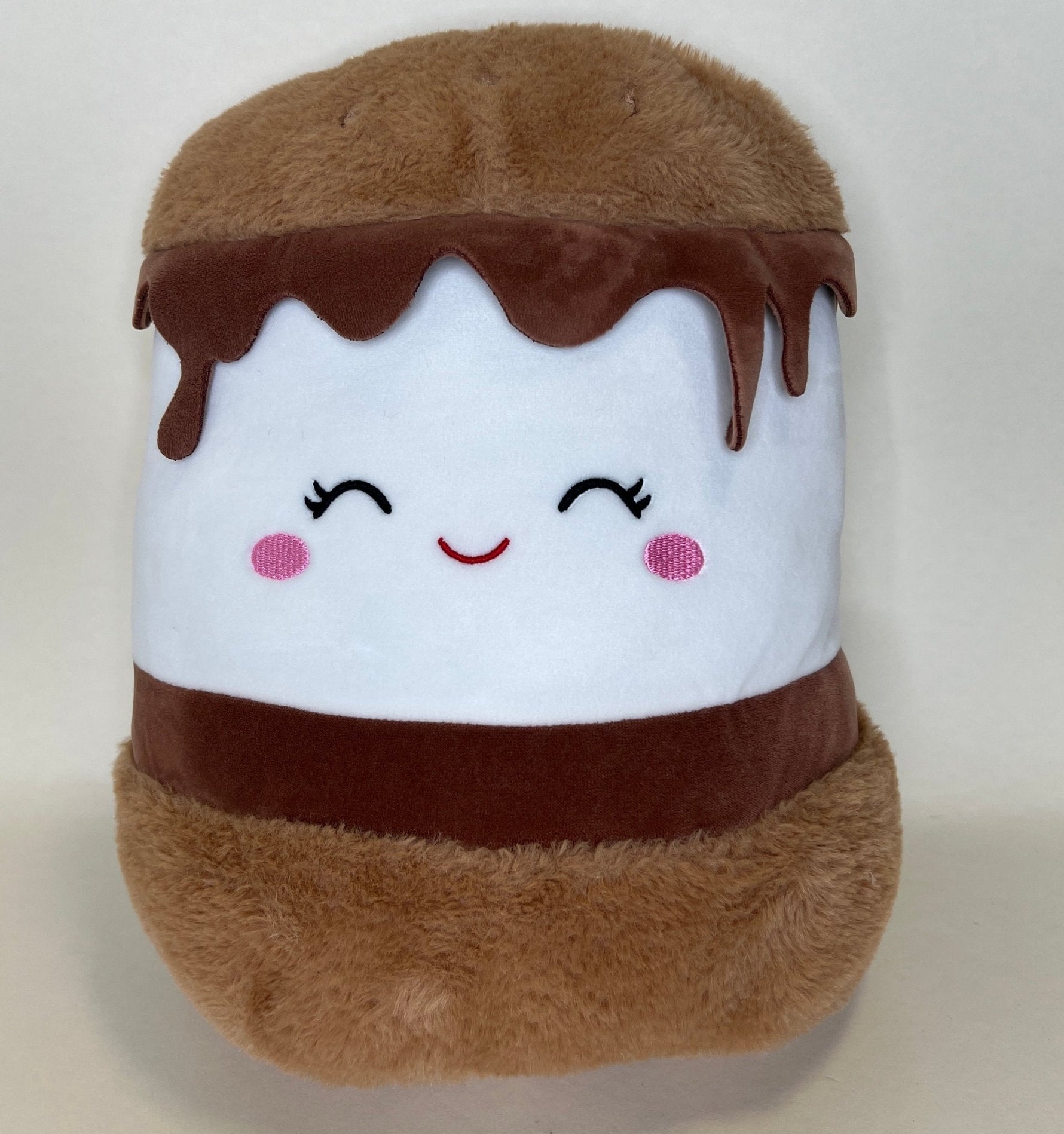 Brown and white plush dessert with closed eyes, rosy cheeks, and drippy top