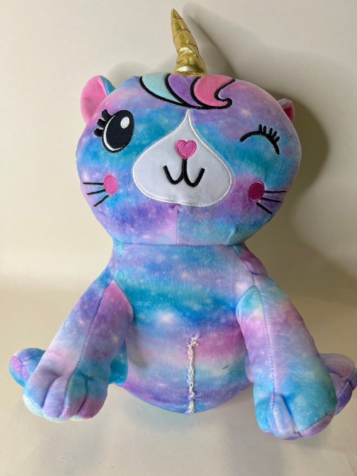 Rainbow galaxy unicorn plush pet toy with horn, closed eyes, and heart chest