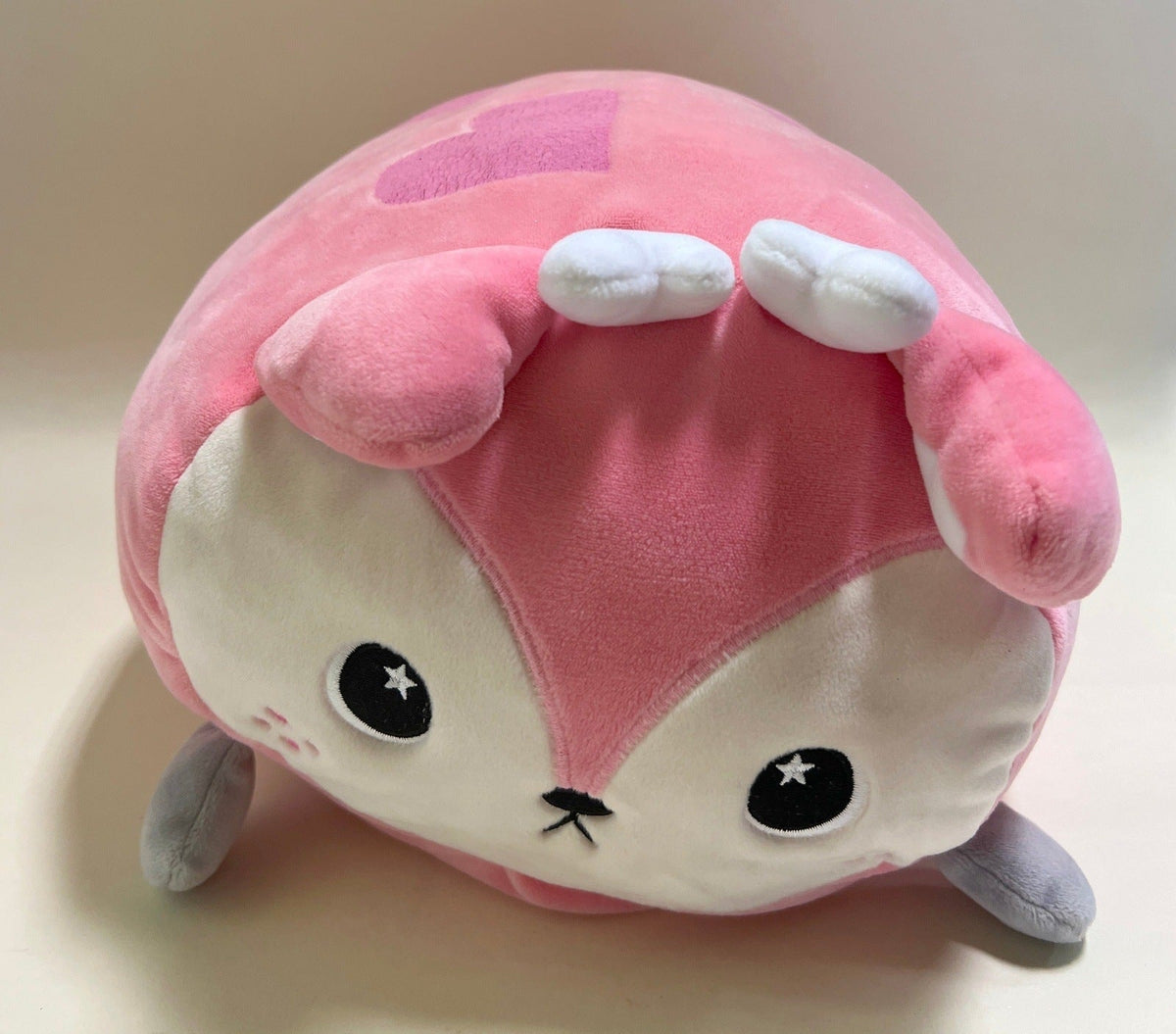 Large squishy plush pet toy, pink and cream character with closed eyes and star accents.