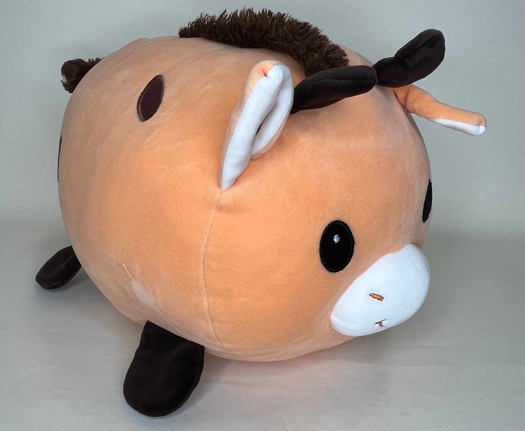 Large orange plush cuddler dog with long ears, black nose, and stitched smile
