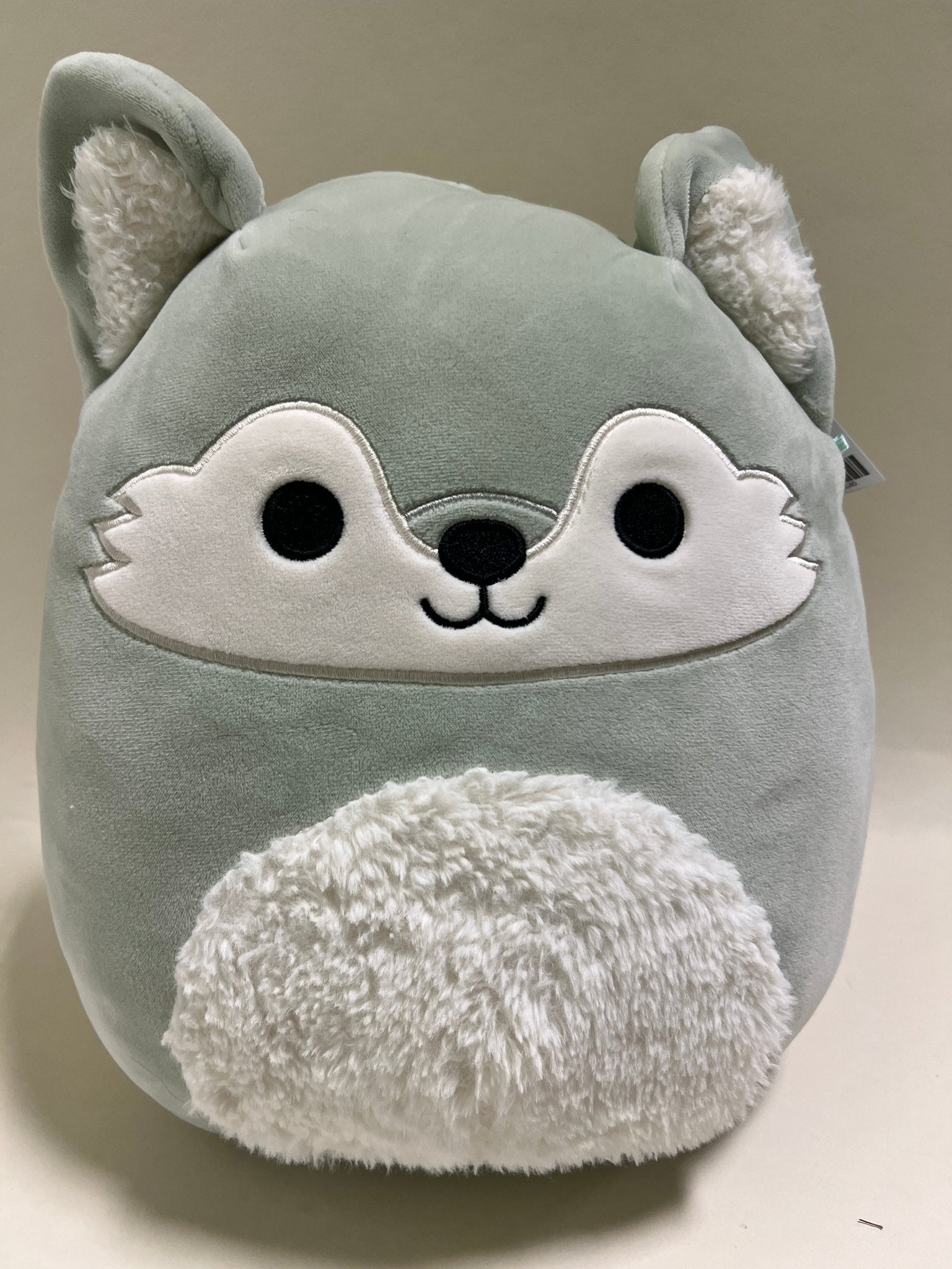 Gray cat-shaped squishy plush with white face, big eyes, and fuzzy belly