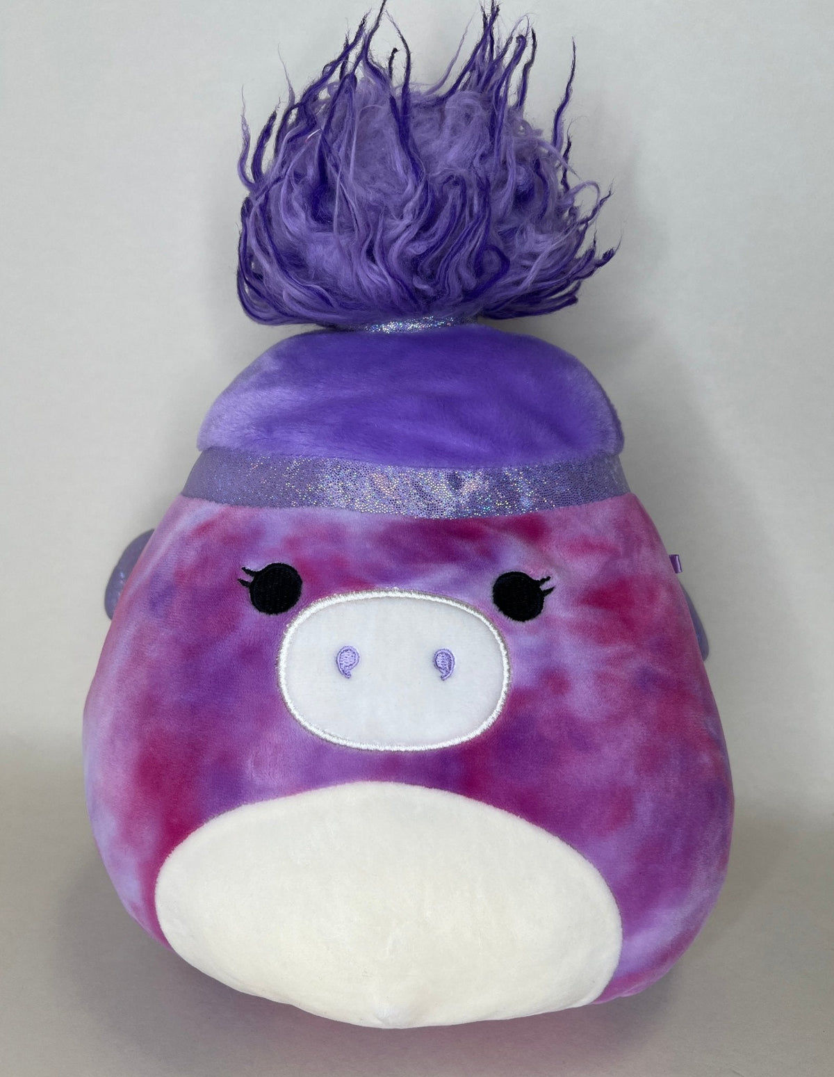 Purple plush creature with spiky hair, small eyes, and white belly