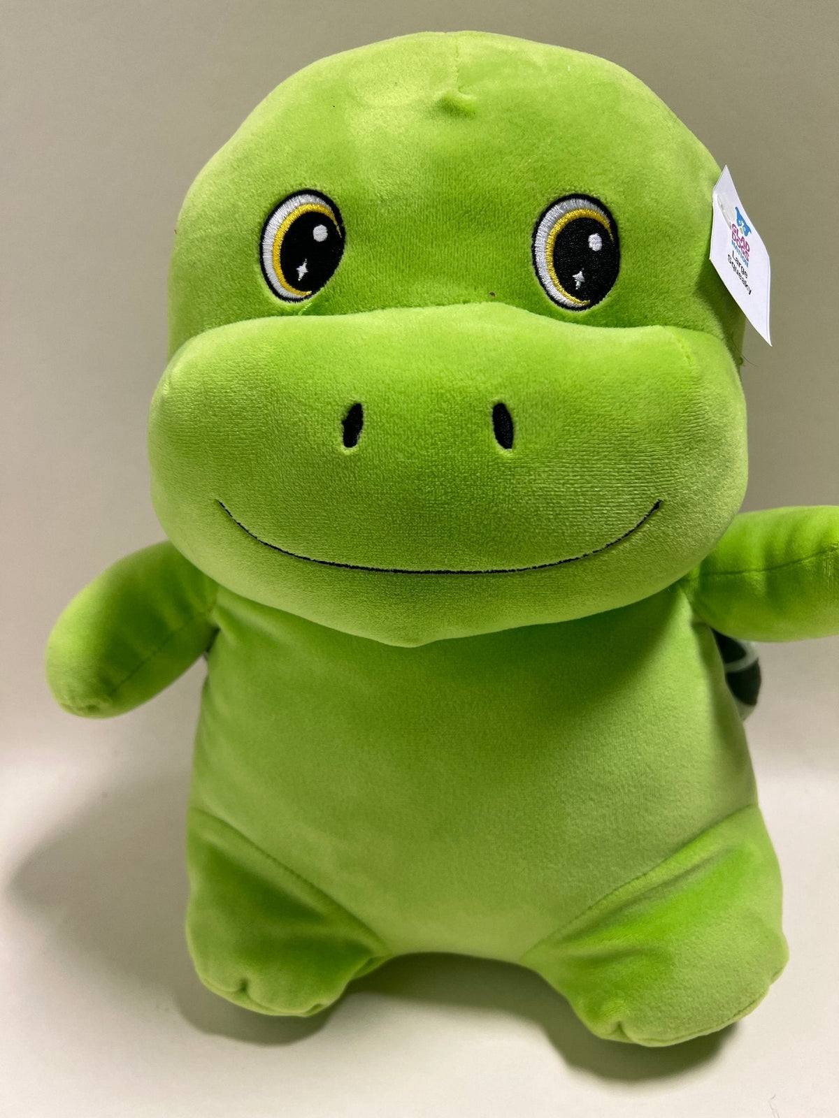 Green dinosaur-style plush squishy pet toy with big eyes and friendly stitched smile