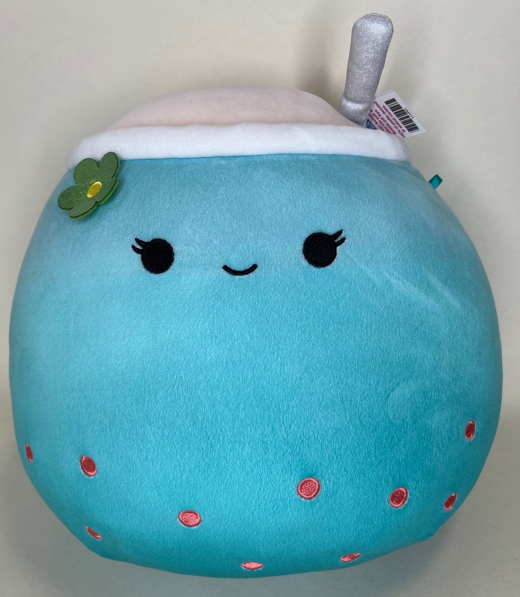 Round blue plush with closed smile, small blush spots, and a leaf charm